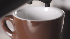 Espresso flowing from a machine into a cup