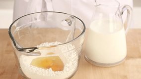 Milk being added to flour and a beaten egg