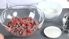 Grated cheese being added to a minced meat and tomato mixture