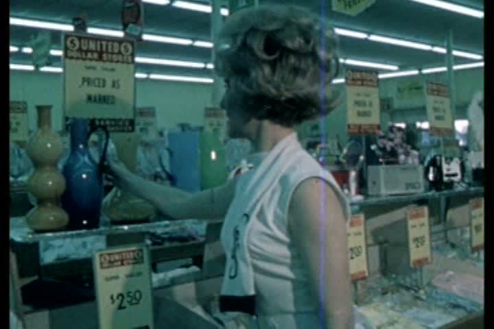 1960s - A woman browses through various items at a dollar store during the 1960s