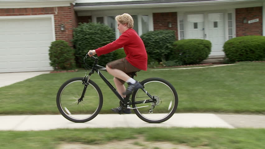 Young cyclist riding his bike on a sidewalk in a middle-class, mid-western