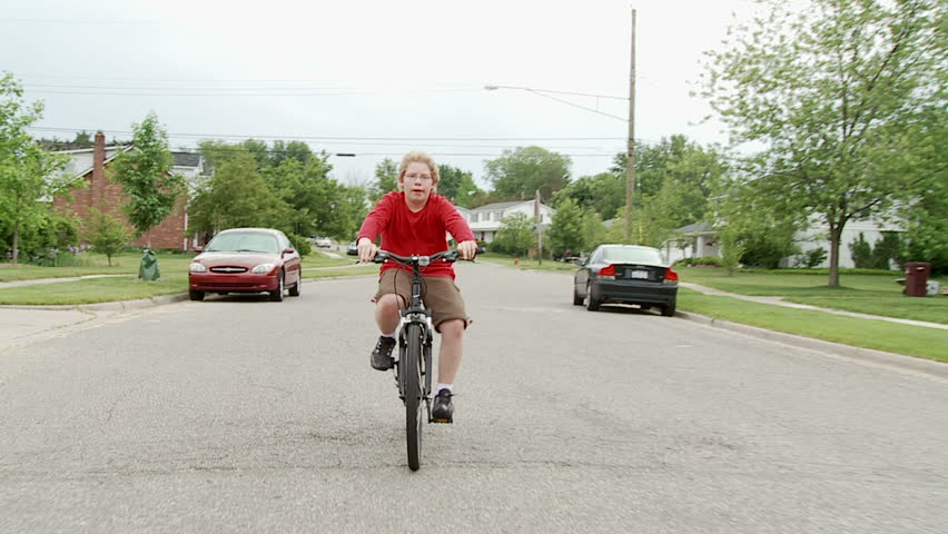 Boy riding a bicycle in the road through middle-class, mid-western American