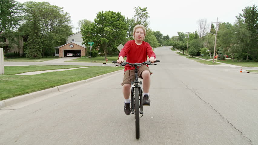 Boy riding a bicycle in the road through middle-class Mid Western American