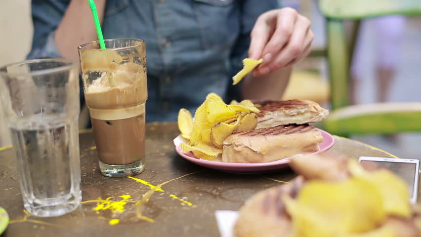 Female hands eating chips and sandwich
