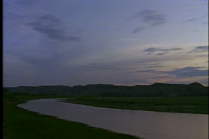 Pan of the calm Little Missouri River at dusk in Medora, North Dakota.