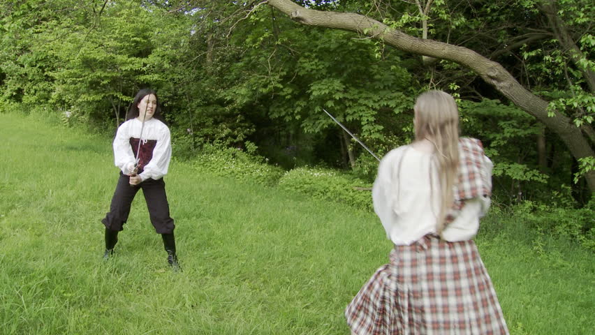 Hand held coverage of a sword fight between a man in a kilt and an asian girl in