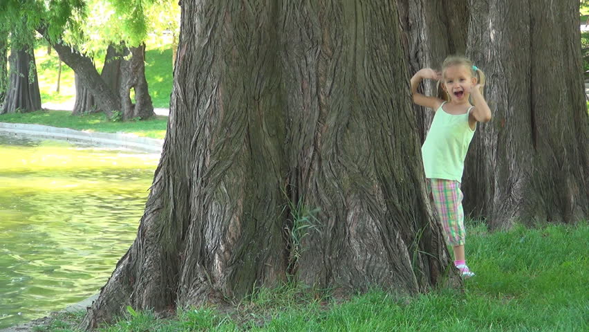 Child Playing Peak a Boo in Park, Girl Hiding by a Tree, Hide and Seek, Children