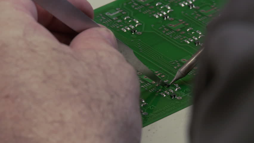 Detail of components being soldered on to a circuit board.