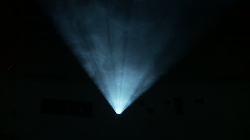 Low, front on view of the light beam of a 35mm projector running in a darkened