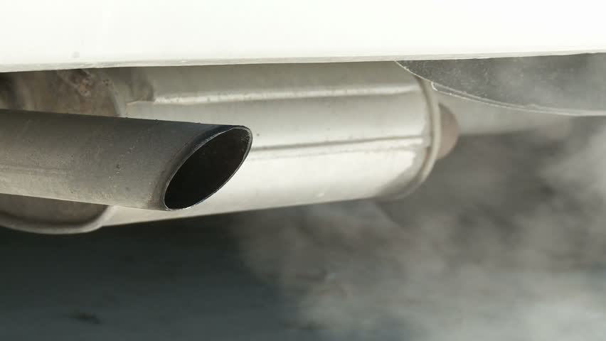 View of car exhaust pipe, emitting fumes, with details of car underside