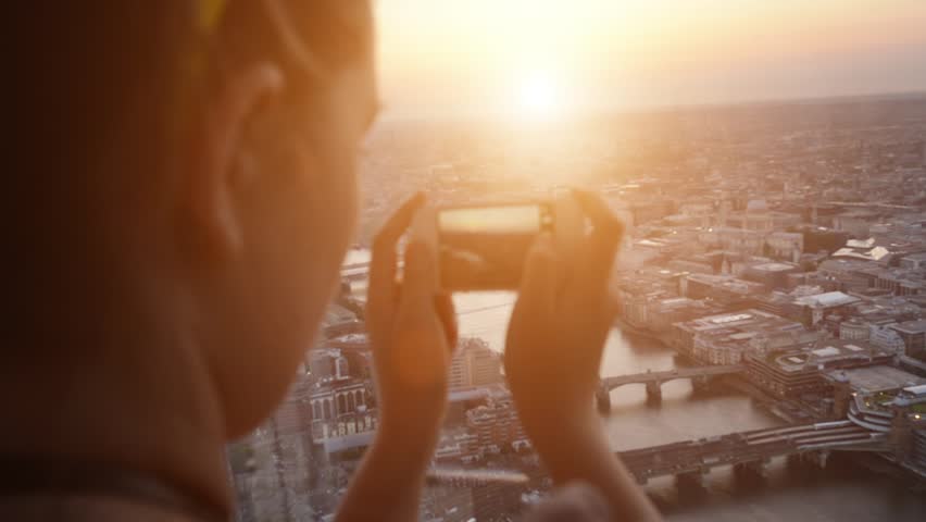 Tourist taking photograph of sunset in london skyline view from The Shard