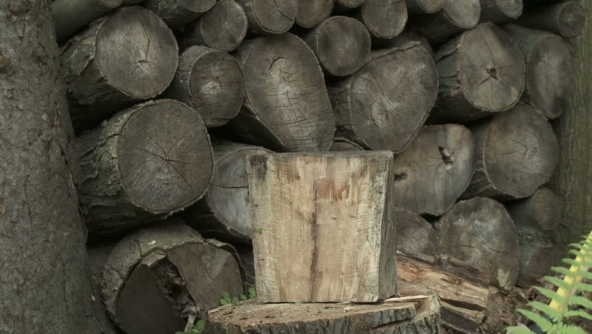 Three shots, close ups of logs being split with an axe.  Background of wood