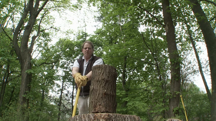 Man chopping up logs with an axe.  Overcranked slow motion.  Background of