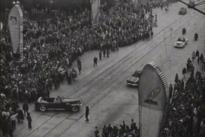 1930s - High angle views of a very large parade and car procession through a major city.