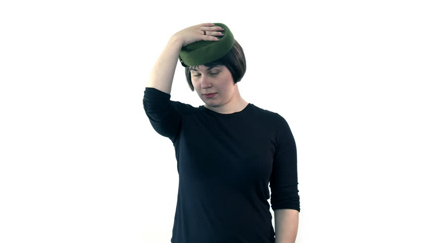 Mid shot of a young woman wearing a smart green hat.  Walks into shot, looks at