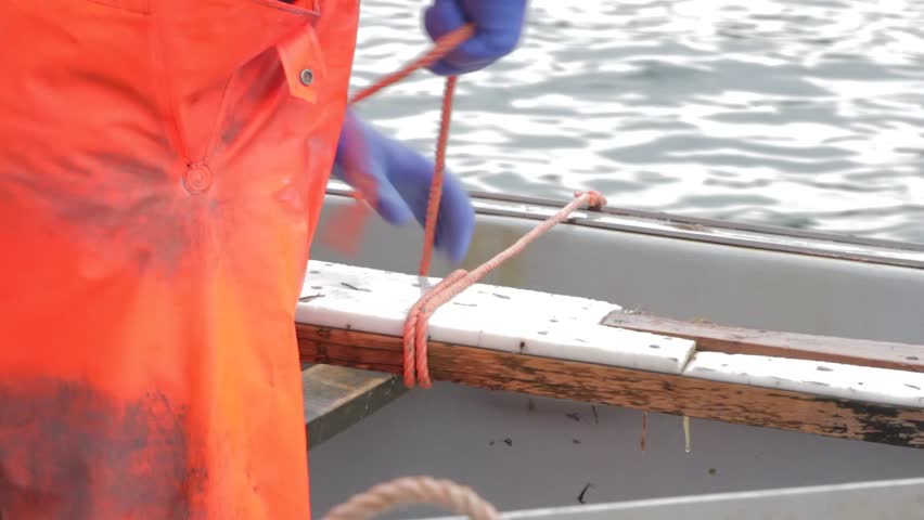 A fisherman tying a knot on his boat