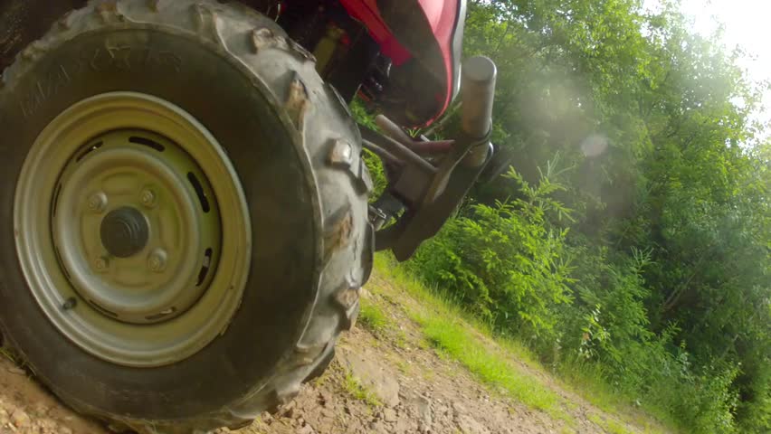 A four wheeler driving on a dirt road through a forest