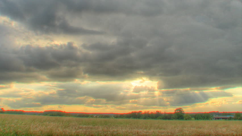 Clouds passing over fields with sun rays, HDR (high dynamic range) time lapse