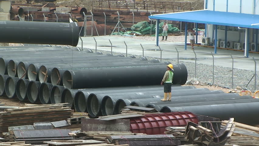 Construction worker handling large pipes