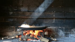 preparing large dish of paella with firewood (Loop-ready video)