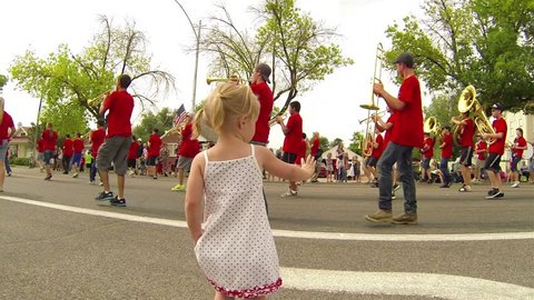 MORONI UTAH JUL 2013: Little girl waves rural small town marching band community annual 4th July parade. Families return to hometown for family fun and recreation. Granddaughter enjoying celebration. 