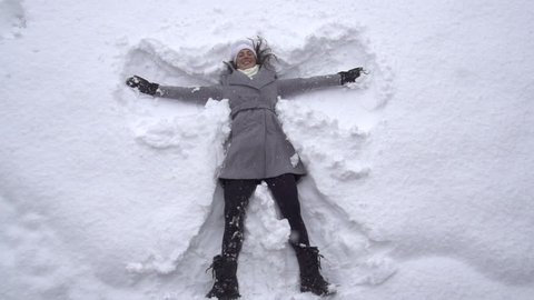 SLOW MOTION: Young woman making snow angels