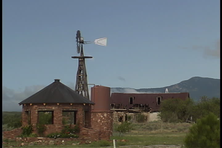 Abandoned farm buildings and windmill with Sandia Mountains in background in Albuquerque, New Mexico.