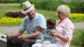 Charming grandparents enjoying spending time with their little granddaughter outdoors