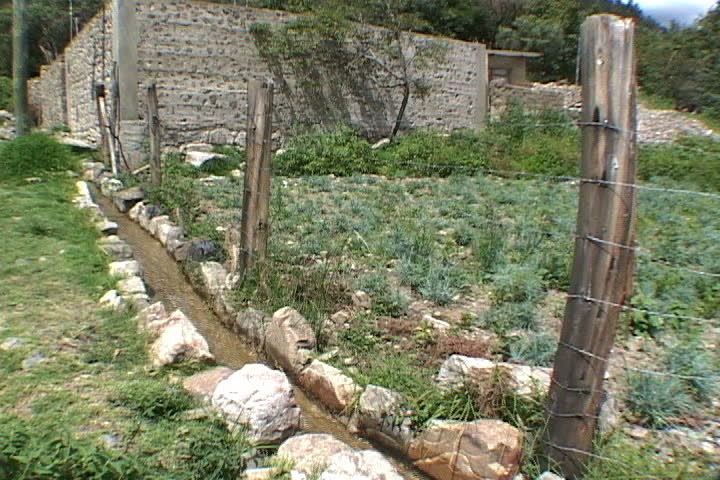  Irrigation ditch runs around perimeter of small farm in Bolivia.
