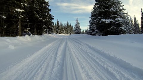 Low angle driving POV on snowy country road in Alaska