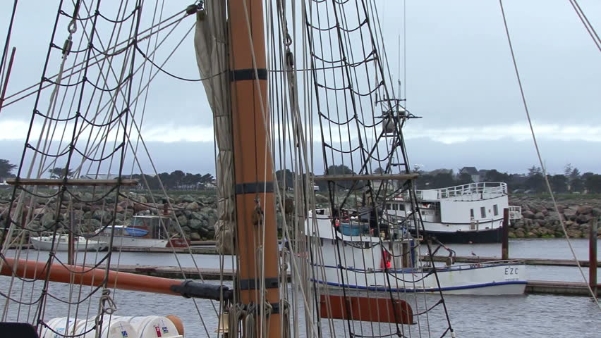 Tilt up from mast of tall sailing ship at harbor to the crows nest