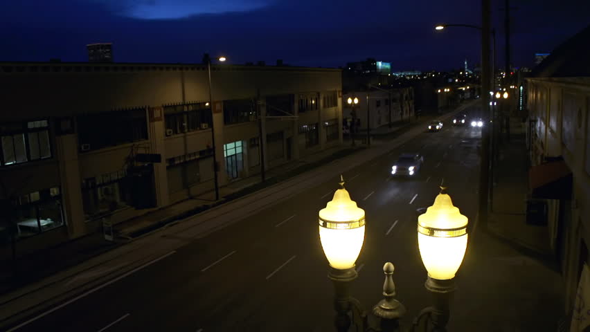Traffic on dark streets of Portland, Oregon at night with Art Deco street lamp 