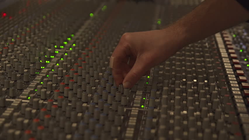 Recording engineer adjusts settings on mix board in recording studio