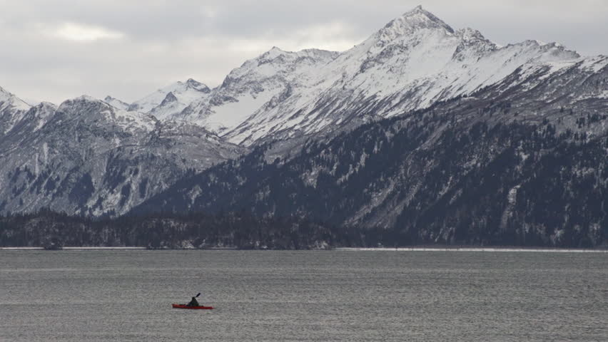 Lone kayaker paddles towards Land's End in Kachemak Bay, Homer, Alaska, with the