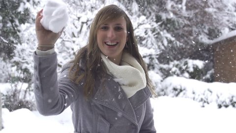 SLOW MOTION: Young woman throws snowball into camera