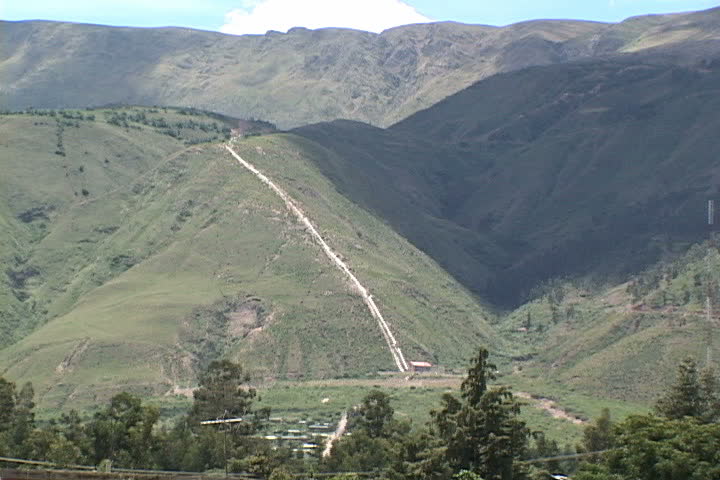 Water pipeline runs down side of mountain beyond village in Cochabamba, Bolivia.