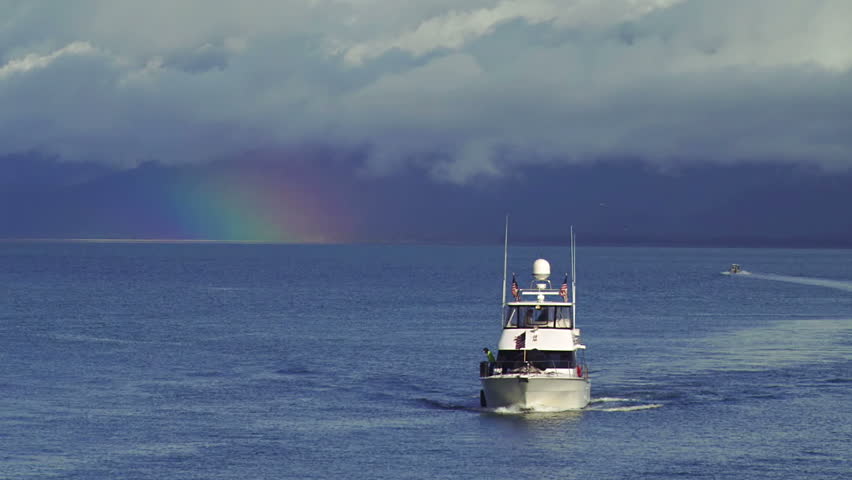 Private yacht heading to harbor with rainbow