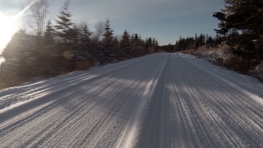 Driving POV on snowy rural Alaskan road near forest