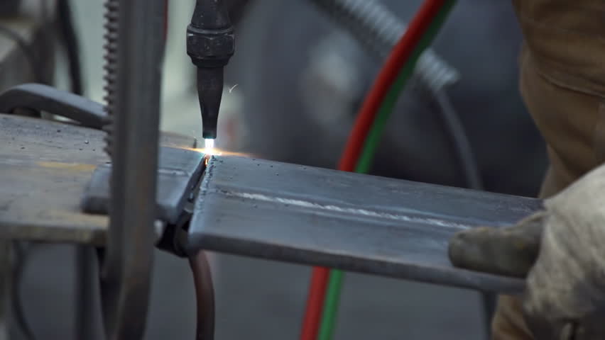 Steel worker severing plate steel using a blow torch in slow motion