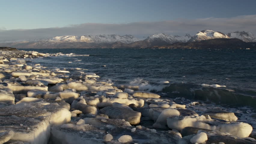 Waves of Kachemak Bay wash against the ice-strewn beach of Land's End, Alaska