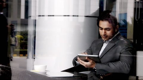 Shot of a businessman sitting in an office canteen and using a digital tablet