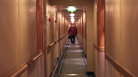 Mature man with beard walks cruise ship hallway. Vacation cruise to Alaska. Man walks inside hall between cabins on luxury boat. Passengers enjoy the escape some revert to alcohol as a party venture.