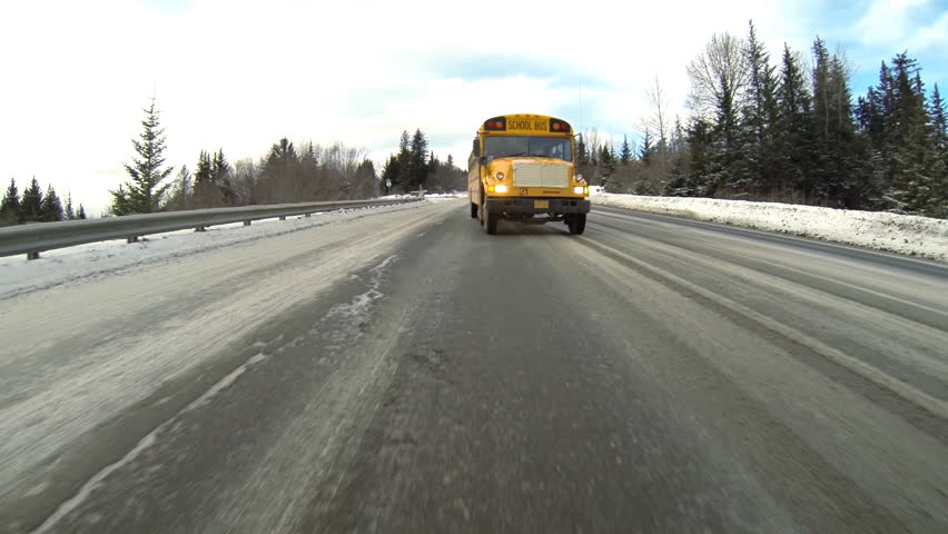 HOMER, AK - FEBRUARY 2013 - School bus drives on icy Alaskan road in February