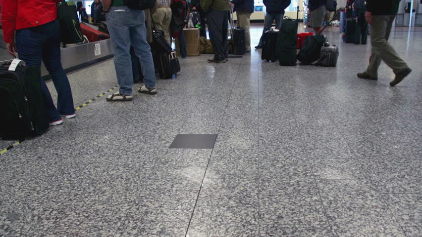 Man leaves baggage claim carousel with suitcase and walks through airport