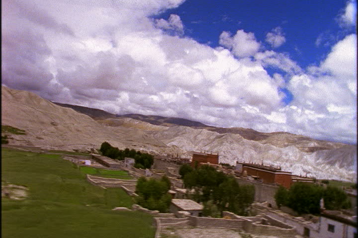 Low aerial over fields and walls of Lo Monthang, banking hard over buildings in village in Lo Monthang, Nepal.