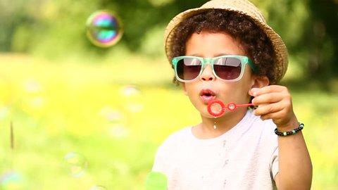 Young boy with hat and sunglasses playing in park
