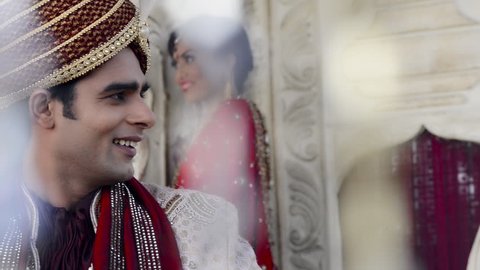 Shot of a Indian groom with bride standing in the background