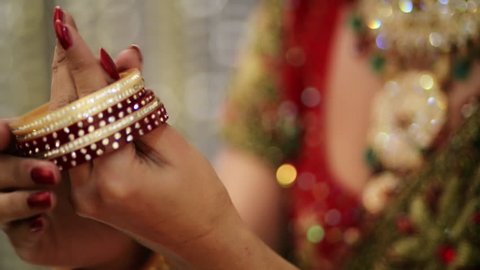 Shot of a Indian bride putting on bangles in her hand