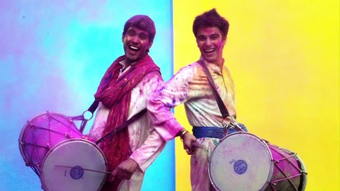 Locked-on shot of two male friends celebrating Holi with playing dhol