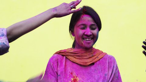 Locked-on shot of friends playing holi with their female friend with colors